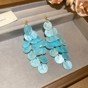Detail of light blue tiered shell earrings with cascading round sequins in a jewelry box