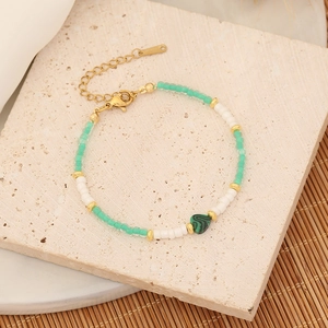 Bohemian beaded bracelet with mint green heart pendant on a rustic stone background