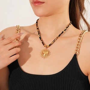 Primo piano della collana in corda leopardata con ciondolo a cuore dorato e raggi solari