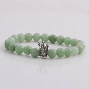 Detail of 8mm faceted light green stone beads with a silver crown charm on a bracelet