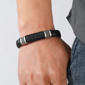 Close-up of black braided leather men's bracelet with silver magnetic buckle on wrist