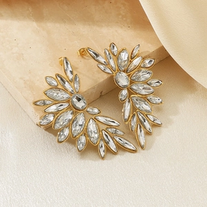Detailed view of gold stainless steel floral stud earrings with sparkling crystals on marble