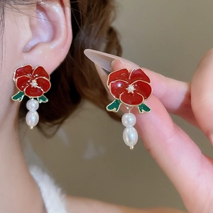 Detail of red enamel rose earrings with dangling pearls and green leaf accents
