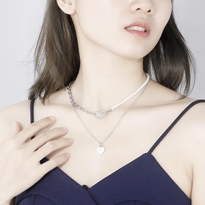 Detail of silver double-layered heart necklace with pearls and metallic pendant
