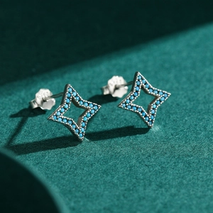 S925 sterling silver four-point star stud earrings with turquoise stones on green texture