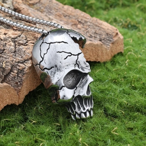 Close-up of retro silver skull pendant with detailed cracks on natural wood and grass