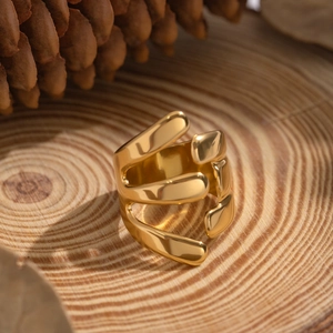 Macro view of gold irregular layered geometric ring on natural wood with pine cones