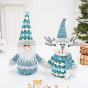 Close-up of blue and white knitted Christmas gnome and reindeer figures on snow