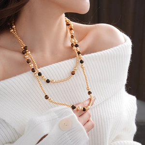 Close-up of double-layer necklace with faux tiger eye stones and golden pearls on a model