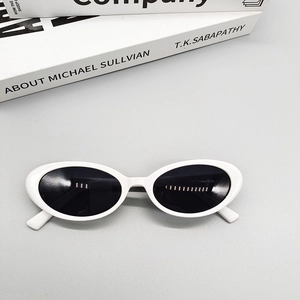 Detail view of oval white sunglasses frame with black lenses and retro cat-eye style