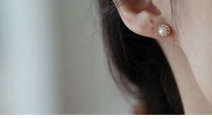 Close-up of a vintage round pearl earring with zirconia halo on a woman's ear