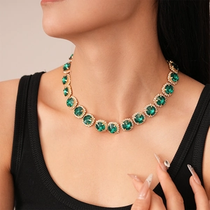 Detail of luxury gold necklace with green gemstone and sparkling crystals on model