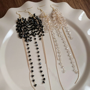 Dettaglio di orecchini lunghi con nappe di perline di vetro su un piatto di ceramica