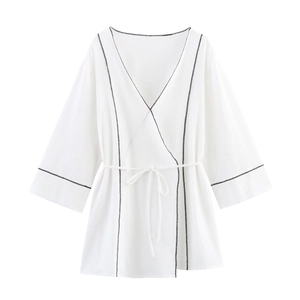 Détail du cardigan portefeuille blanc avec coutures noires contrastées et lien de serrage