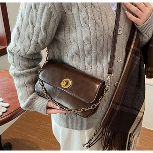 Close-up of vintage dark brown faux leather bag with gold clasp and chain strap
