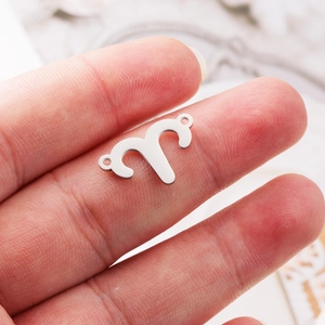 Close-up of Aries zodiac pendant connector in mirror polished stainless steel on a finger