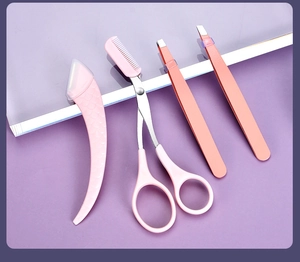 Pink eyebrow trimmer kit with scissors, comb and tweezers on purple background