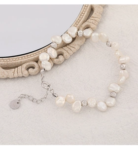 Detail of 925 sterling silver tag and irregular baroque pearls on a textile surface
