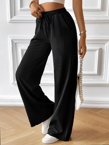 Detail of black wide-leg trousers featuring an adjustable drawstring waist and soft knit fabric