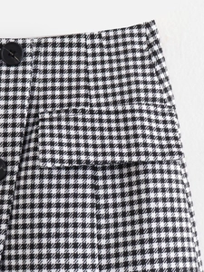 Gros plan détaillé de la mini-jupe pied-de-poule avec boutons noirs et rabat de poche