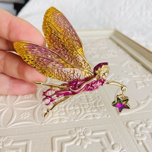 Close-up of golden fairy brooch with gradient enamel wings and star pendant detail