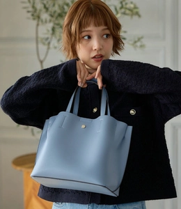 Detail of light blue faux leather tote bag with golden metal buckle and stitching