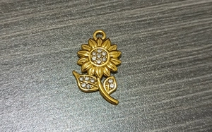 Detailed macro view of a gold-plated sunflower pendant with sparkling clear crystals