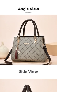 Detail view of the gray patterned handbag featuring a gold logo and a red tassel charm