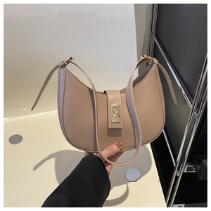 Détail d'un sac demi-lune beige avec boucle métallique brillante et fine bandoulière