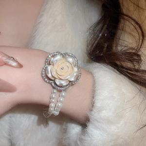 Detailed view of luxury multilayer pearl bracelet with a large diamond-set shell flower charm