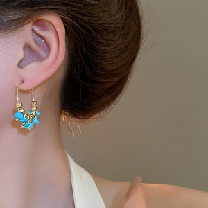 Detailed close-up of bohemian gold hoop earrings with irregular turquoise stones on a model