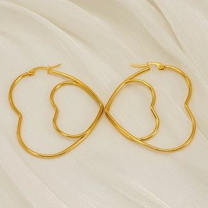 Polished gold double heart hollow earrings on white silk fabric background