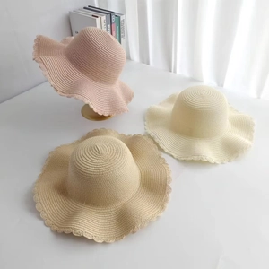 Close-up of three wide-brim straw hats in pink, beige, and khaki with wavy lace edges