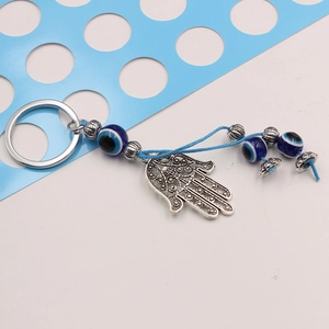 Hamsa hand keychain with blue evil eye beads and woven rope on a clean background