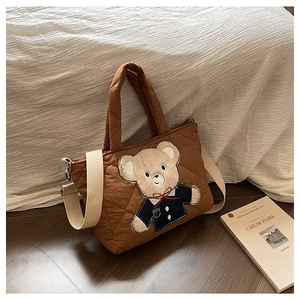 Close-up of brown quilted bag featuring cute teddy bear embroidery and contrast straps