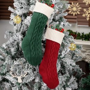 Pair of red and green cable knit Christmas stockings hanging on a snowy holiday tree