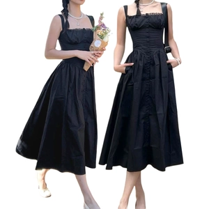 Détail de la robe longue noire à fines bretelles avec taille cintrée et boutons décoratifs
