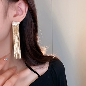 Close-up of golden tassel earrings with sparkling rhinestones worn on a model's ear