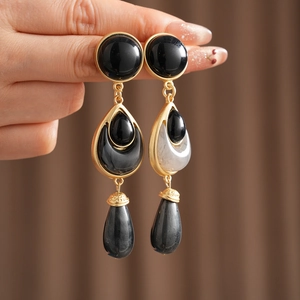 Close-up of vintage floral drop earrings with black and white stones in gold setting