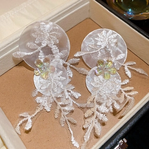 Gros plan de broderie florale en dentelle sur boucles d'oreilles en résine et nacre