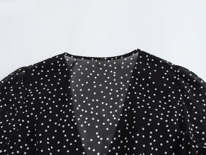 Close-up of V-neckline on black polka dot chiffon dress with elegant lace detail