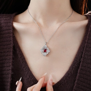 Detail of silver flower necklace featuring a central red gemstone and sparkling zircons
