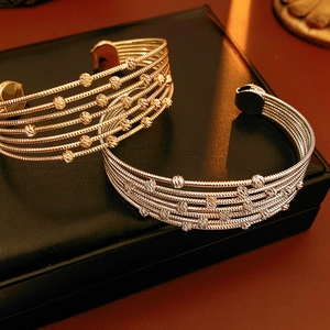 Détails de bracelets multicouches à perles dorées et argentées sur cuir noir
