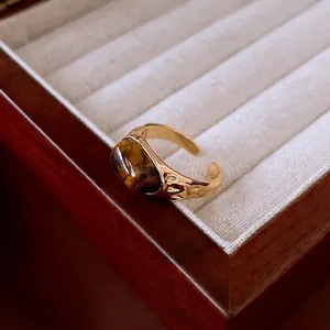 Gold plated open ring with oval tiger eye stone on hammered metal in a jewelry box