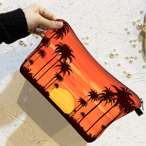 Sonnenuntergang-Kosmetiktasche mit Palmenmuster in der Hand vor strukturierter Wand