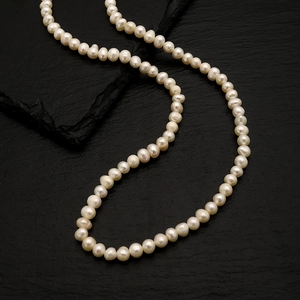 Macro detail of natural freshwater pearl necklace on a textured black slate background
