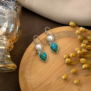 Vintage bohemian drop earrings with turquoise and white pearls on rustic wooden tray
