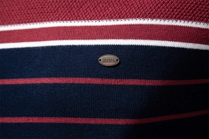 Close-up of color block striped knit sweater with premium metal logo detail