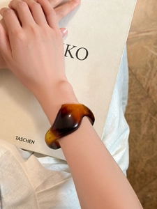 Artistic shot of amber acrylic irregular wavy bangle on vintage lifestyle background