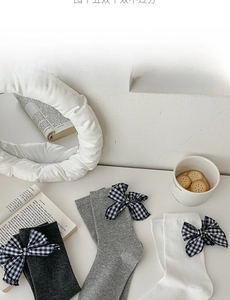 Detail of grey and white cotton mid-calf socks with blue gingham bow decorations